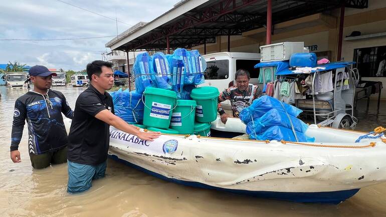 Hilfsgüter von Aktion gegen den Hunger werden mit einem Boot in den Überschwemmungsgebieten nach dem Tropensturm Trami auf den Philippinen transportiert.