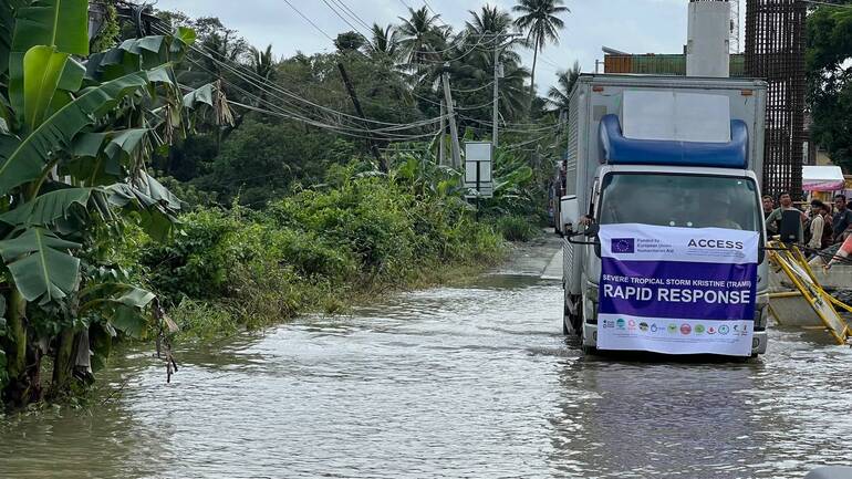 Ein Lastwagen mit der Aufschrift "Nothilfe" fährt durch eine geflutete Straße auf den Philippinen.
