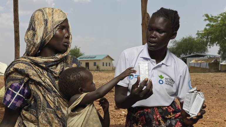 Nyibol Mathiang Deng, 27, und ihr Kind aus dem Sudan erhalten Energiekekse von Mary Anok Juac, die für Aktion gegen den Hunger arbeitet. Nyibol Mathiang Deng, 27, und ihr Kind aus dem Sudan erhalten Energiekekse von Mary Anok Juac, die für Aktion gegen den Hunger arbeitet.