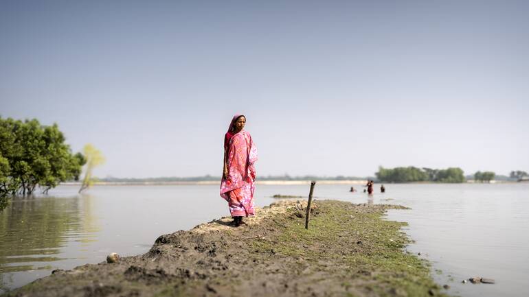 Eine Frau auf einem Deich in Bangladesch.