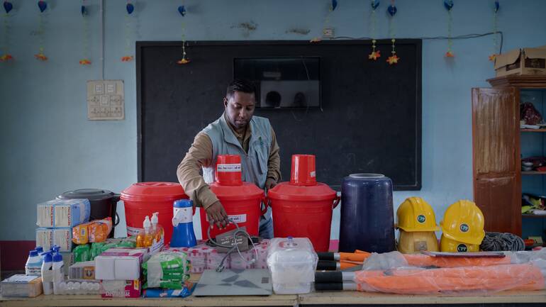 Ein Mann aus Bangladesch beim Bereitstellen von Werkzeug für die Fischzucht.