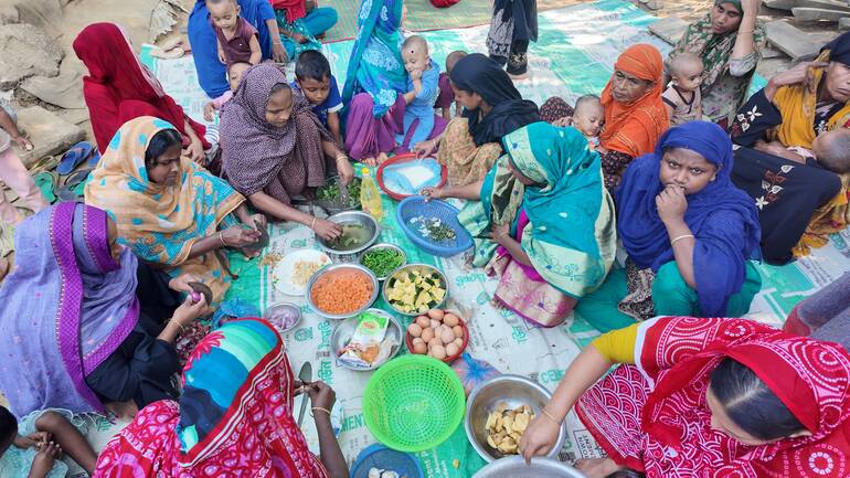 Frauen und Kinder aus Bangladesch beim Zubereiten einer Mahlzeit
