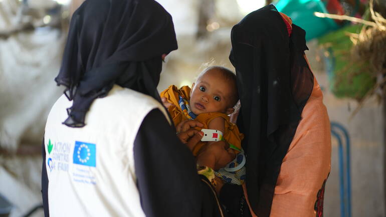Alis Ahmeds Frau und ihr Kind zusammen mit einer Mitarbeiterin von Aktion gegen den Hunger, die den viel zu dünnen Oberarm des Kindes mit einem MUAC-Band misst. Alis Ahmeds Frau und ihr Kind zusammen mit einer Mitarbeiterin von Aktion gegen den Hunger, die den viel zu dünnen Oberarm des Kindes mit einem MUAC-Band misst.