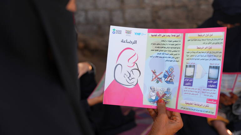 Eine Mutter hält eine Infobroschüre zum Stillen in der Hand. Eine Mutter hält eine Infobroschüre zum Stillen in der Hand.