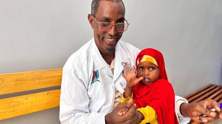 Dr. Hindiye mit einem kleinen Mädchen auf dem Arm Dr. Hindiye mit einem kleinen Mädchen auf dem Arm