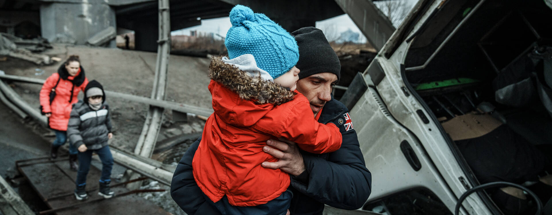 Krieg Ukraine: Mann mit Kind auf dem Arm inmitten von Zerstörung. Krieg Ukraine: Mann mit Kind auf dem Arm inmitten von Zerstörung.