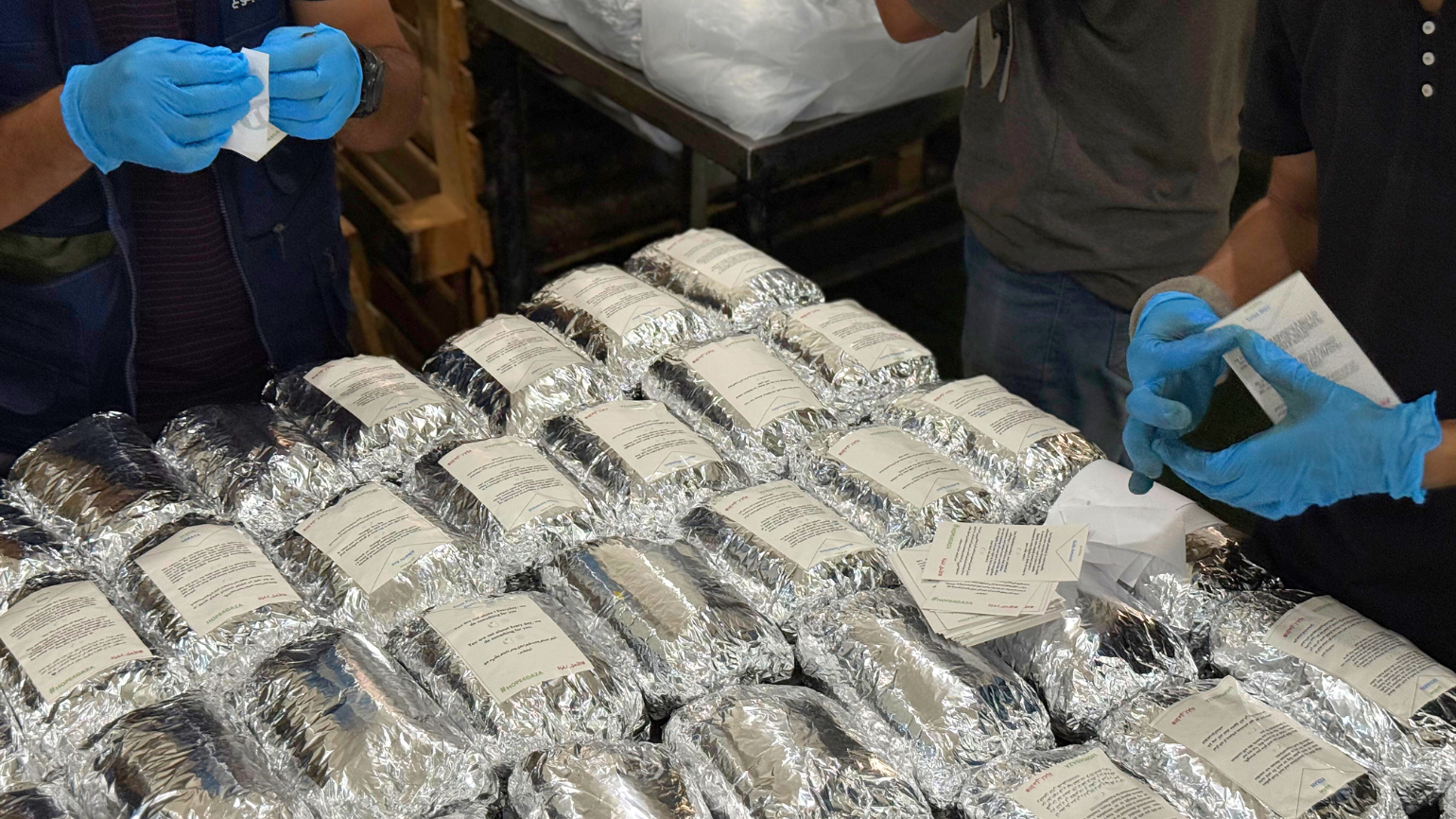 Mitarbeiter von Aktion gegen den Hunger kleben Solidaritätsbekundungen auf verpackte warme Mahlzeiten. Mitarbeiter von Aktion gegen den Hunger kleben Solidaritätsbekundungen auf verpackte warme Mahlzeiten.