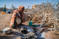Eine junge Frau im ländlichen Somalia sitzt an einem offenen Feuer. Die Region ist von einer langanhaltenden Dürre betroffen.