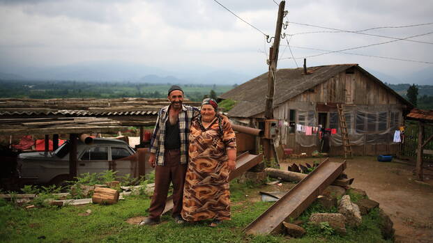 Ein Ehepaar in Georgien steht vor ihrer Hütte.