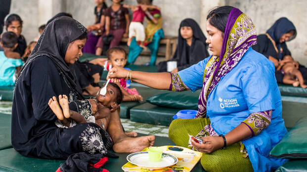 Mitarbeiterin von Aktion gegen den Hunger füttert Kind in Bangladesch.