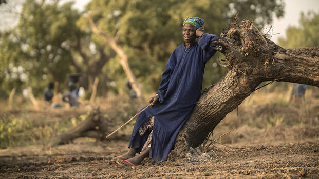 Frau in Burkina Faso leht sich an einen Baum.