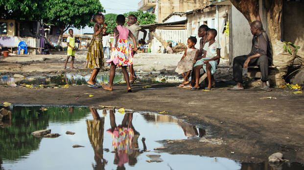Kinder in der Elfenbeinküste an einer Pfütze.