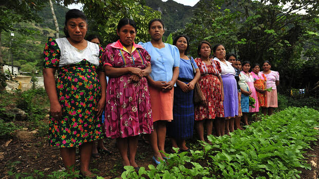 Frauen in Guatemala stehen in einer Schlange am Feld.