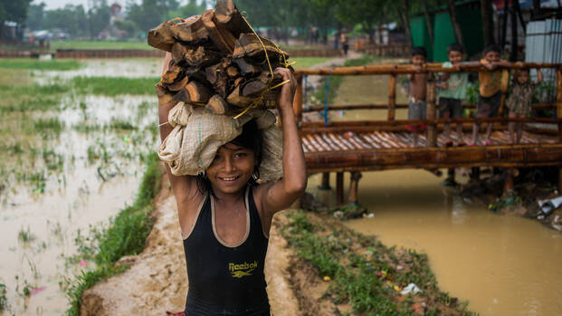 Kind in Myanmar trägt einen Stapel Holz.