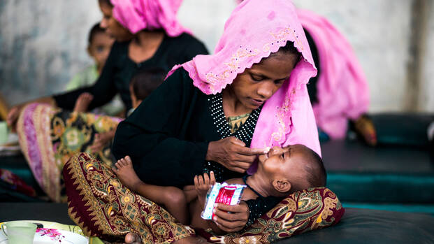 Mutter füttert ihr Kind mit Aufbaunahrung.
