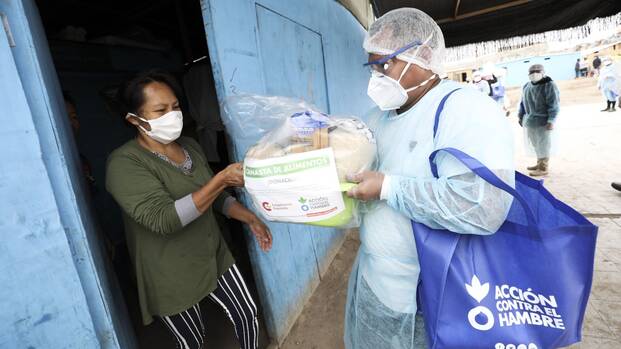 Mitarbeiter von Aktion gegen den Hunger übergibt Lebensmittelpaket.