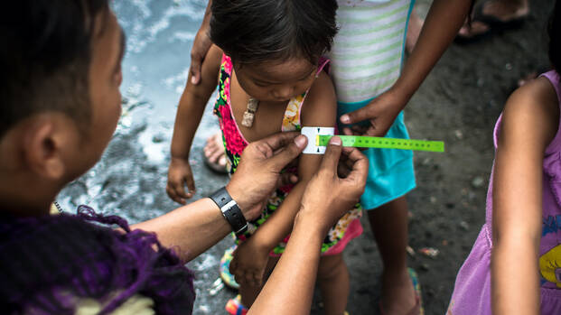 Mitarbeiter ermittelt Grad der Mangelernährung bei einem philippinischen Kind.