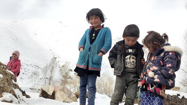 Kinder stehen auf einem schneebedecktem Hügel
