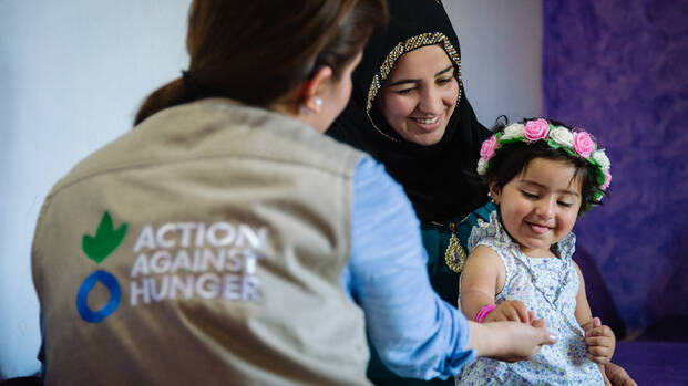 Aktion gegen den Hunger Mitarbeiterin mit Kind und Frau