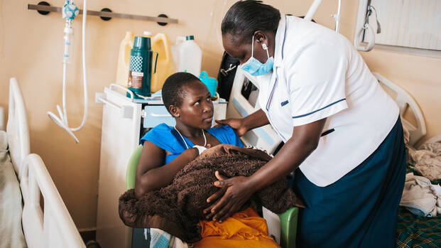Mitarbeiterin von Aktion gegen den Hunger hilft Mutter und Kind im Stillraum in Kenia 