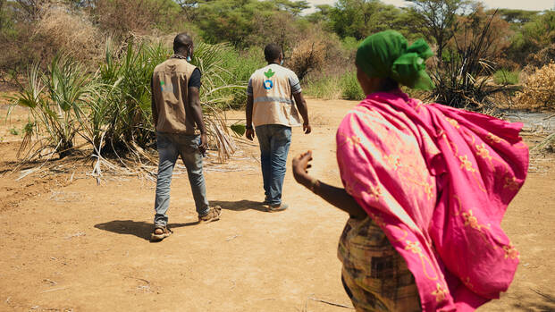 Frau und Mitarbeiter von Aktion gegen den Hunger in trockener Landschaft in Kenia