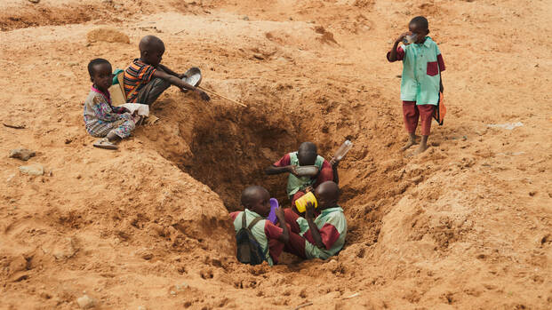 In Laresoro, Kenia, graben die Dorfbewohner Löcher, um Wasser zu finden. Hier halten Kinder auf dem Weg zur Schule an, um zu trinken und ihre Flaschen aufzufüllen, obwohl das Wasser verschmutzt und voller Bakterien ist.