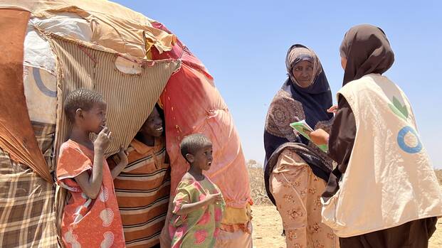 Mitarbeitende von Aktion gegen den Hunger sprechen mit einer Mutter und ihren Kindern vor ihrem Zelt in Somalia.