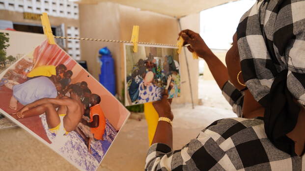 Eine Frau aus dem Senegal hängt selbstgeschossene Fotos auf einer Leine auf