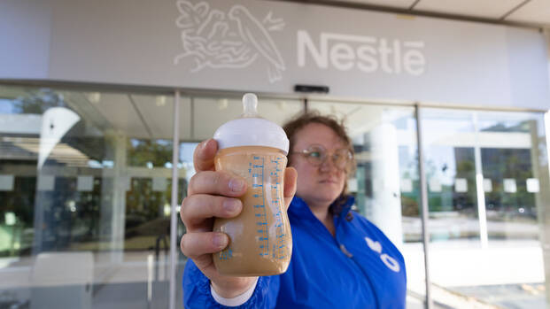 Aktion-gegen-den-Hunger-Mitarbeiterin Kira hält eine Flasche mit verschmutzter Babymilch vor der Nestlé-Zentrale in Frankfurt am Main in die Kamera
