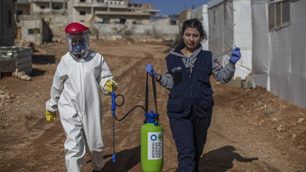Zwei MItarbeitende von Aktion gegen den Hunger tragen Desinfektionsmittel durch ein Dorf im Libanon, um Cholera-Bakterien zu beseitigen.