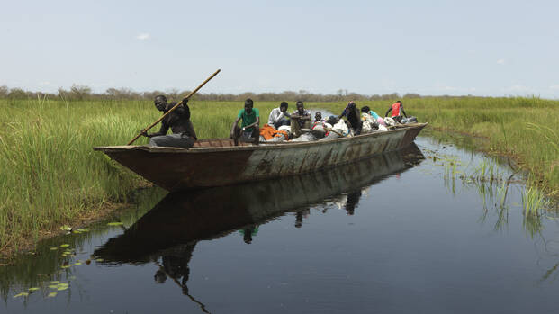 Menschen aus dem Südsudan befahren mit einem großen Boot eine der neuen Wasserstraßen in Paguir