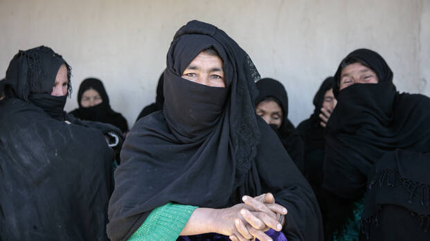 Frauen aus Afghanistan in schwarzen Tüchern sitzen zusammen, die Frau in der Mitte schaut in die Kamera