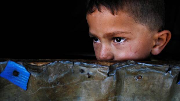 Ein kleiner Junge aus dem Libanon guckt abwartend über eine Mauer