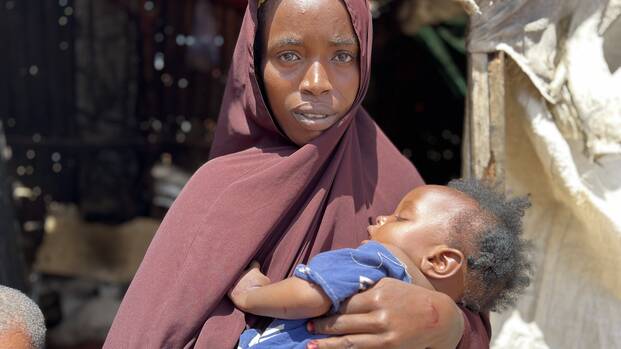 Ifrah aus Somalia hält ihre neun Monate alte Tochter in den Armen. Sie stehen vor der Küche, die heute kalt geblieben ist.