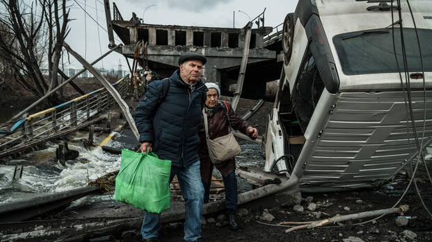 Ein älteres Ehepaar flüchtet durch die Trümmer in Irpin in der Ukraine.