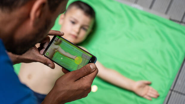 Ein Mitarbeiter von Aktion gegen den Hunger testet die SAM Photo-App mit der Unterstützung eines Jungen.