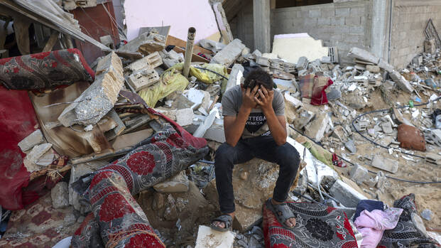 Ein palästinensischer Jugendlicher sitzt auf den Überresten seines zerstörten Hauses und vergräbt den Kopf in den Händen.