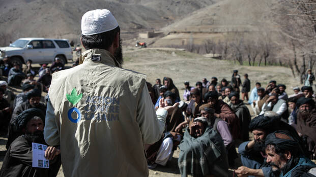 Ein Mitarbeiter von Aktion gegen den Hunger spricht vor einer Menschengruppe in Afghanistan.