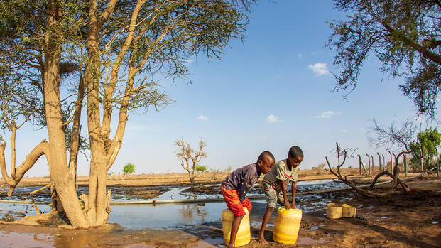 Zwei Kinder aus Kenia beim Wasser holen mit gelben Kanistern