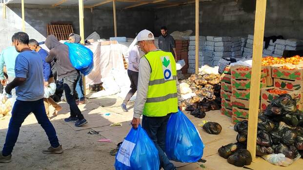 Ein Mitarbeiter von Aktion gegen den Hunger trägt Tüten aus einem Lebensmittellager zusammen mit anderen Helfenden in Rafah im Süden Gazas.