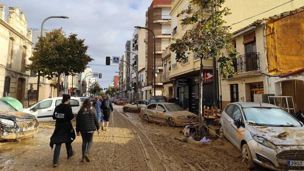 Mitarbeitende von Aktion gegen den Hunger laufen durch eine schlammige Straße in Valencia.