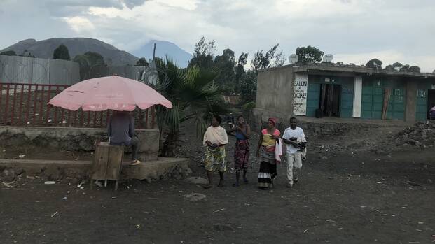 Vier Personen laufen durch ein Camp für Vertriebene in der Demokratischen Republik Kongo