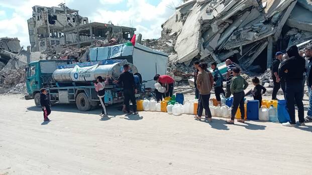 Wassertank in Gaza vor zerstörten Gebäuden im April 2025
