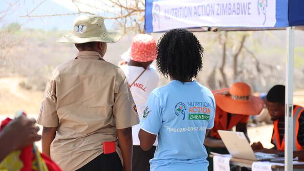Unsere lokalen Projektmitarbeiter*innen vor einem Notfallzelt im Rahmen humanitärer Hilfe in Simbabwe