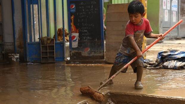 Junge kehrt Schlamm nach Überschwemmung in Peru