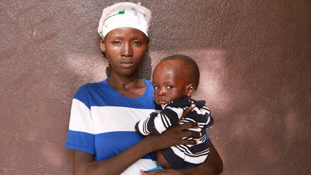 Eine junge Mutter mit ihrem Kind auf dem Arm.