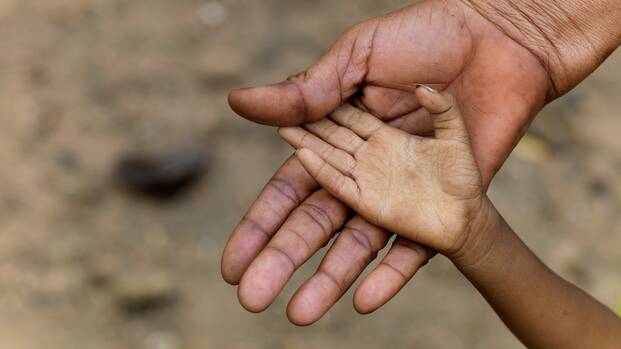 Eine Kinderhand liegt in der Hand eines Erwachsenen.
