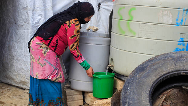 Frau holt Wasser an Wasserstelle im Libanon