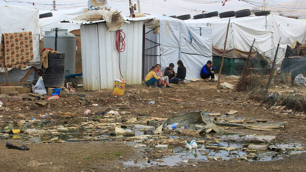 Syrische Flüchtlingskinder sitzen auf dem Boden in einem Flüchtlingslager