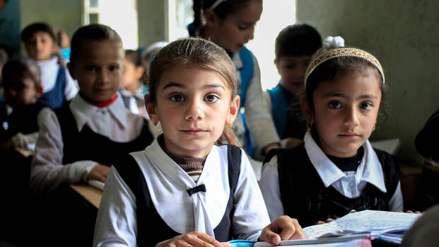 Ein Mädchen im Irak freut sich, dass sie in einer Schule ist und lernen darf.
